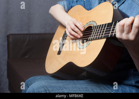 Die junge Frau Hände spielen eine akustische Gitarre im Zimmer Stockfoto