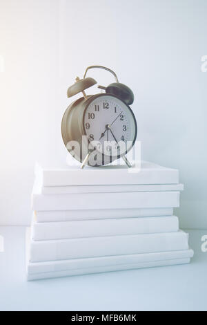 Zeit aufzuwachen und für Prüfungen lernen. Vintage Wecker auf Buch Stapel. Stockfoto