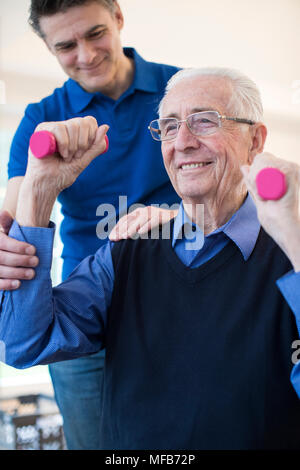 Physiotherapeuten helfen älteren Menschen zu heben Trainingshanteln Stockfoto