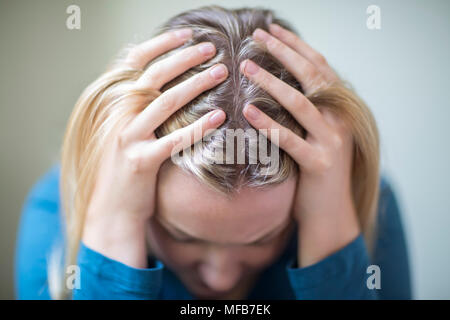 Junge Frau, die unter Depressionen leiden, mit Kopf in den Händen Stockfoto