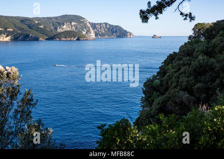 Landschaft Blick auf ein Meer von einem hohen Ort auf Korfu, Griechenland mit blauen Wasser, grüne Berge, kleine Insel und Sportboot mit zwei Personen in der it Stockfoto