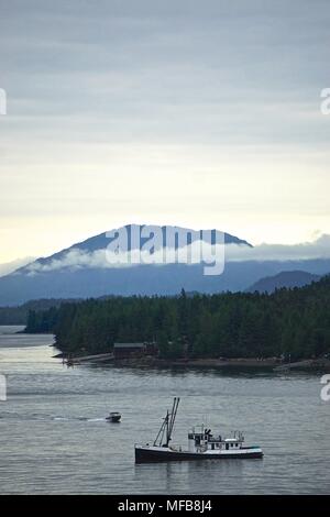 Ketchikan, Alaska: Ein Fischerboot fährt entlang der Tongass Narrows unter einem bewölkten Morgenhimmel mit Bergen im Hintergrund. Stockfoto