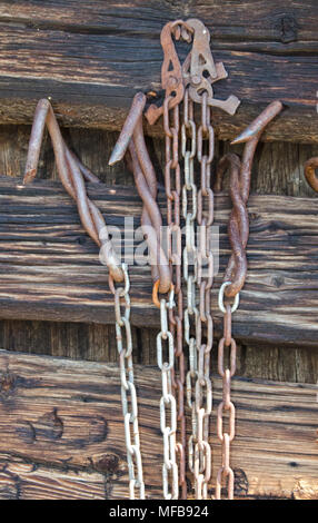 Einige alte Ketten aus Metall und Fallen hängen an der Außenwand eines Blockhaus. Stockfoto