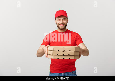 Lieferung Konzept: jungen kaukasischen stattlichen Pizza Delivery Man holding Pizzakartons über grauer Hintergrund Stockfoto