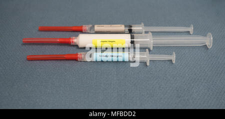 Drei beschriftet Spritzen mit Rot bedeckte Sicherheit Nadeln mit Medikamenten für Anästhesie - fentanyl, Propofol und Lidocain auf einem blau grau Handtuch. Stockfoto