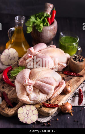 Zwei rohe Hühner auf rustikalen Holzbrett mit Kräutern und Gewürzen Stockfoto
