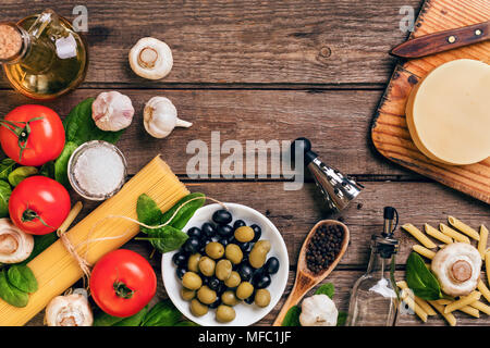 Zutaten für die Zubereitung von Pasta, Spaghetti, Basilikum, Tomaten, Oliven und Olivenöl auf Holz- Hintergrund. Ansicht von oben. Kopieren Sie Platz. Stockfoto