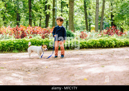 Kind Junge Wandern mit Hund an der Leine im Park Stockfoto