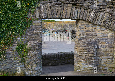 Auf der Suche durch einen Steinbogen in die Ruinen von Slade Schloss, mit seinen Hummer und Krabben Töpfe zum Hafen hinaus. Slade, County Wexford, E Stockfoto