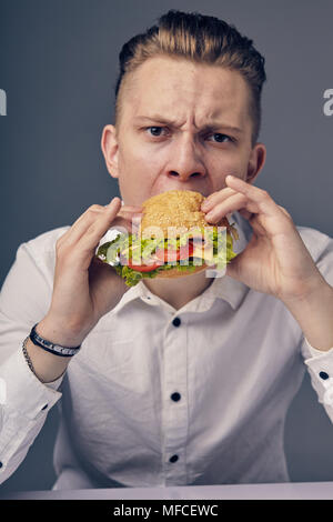 Junger Mann das Essen einer frischen Burger Stockfoto