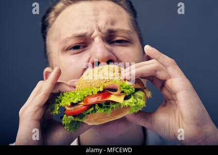 Junger Mann das Essen einer frischen Burger Stockfoto