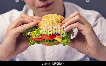 Junger Mann auf der Suche nach einem frischen Burger Nahaufnahme Stockfoto