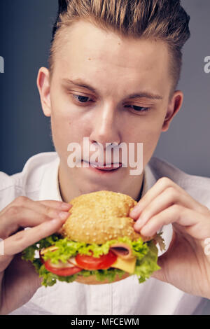 Junger Mann auf der Suche nach einem frischen Burger Stockfoto