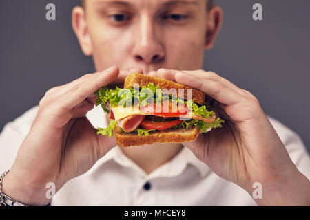 Junger Mann auf der Suche nach einem frischen Burger Stockfoto