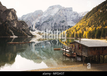 Junger Mann Kajakfahren auf dem berühmten Lago di Braies (Pragser Wildsee) in den italienischen Dolomiten im goldenen Licht am Morgen bei Sonnenaufgang, Südtirol, Italien Stockfoto