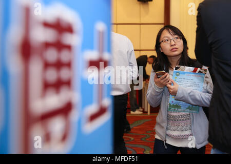 (180425) - Peking, April 25, 2018 (Xinhua) - ein Job Hunter Prüfungen für Informationen während einer Messe in Peking, der Hauptstadt von China, 25. April 2018. Mehr als 160 Universitäten und Hochschulen im ganzen Land an der Messe mit über 5.000 Arbeitsplätzen. Über 1.500 Doktoranden für die Messe angemeldet haben, nach Ansicht der Organisatoren. (Xinhua/Zhang Cheng) (and) Stockfoto