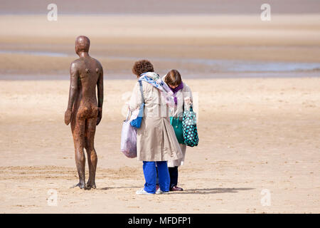 Crosby, Merseyside. 25. April 2018. Einen kühlen und windigen Start in den Tag über den Nordwesten von England als zwei Frauen die 'Iron Man' Kunst installation Bewundern durch renommierte Künstler Sir Antony Gormley auf dem Sand Crosby Strand in Merseyside. Credit: cernan Elias/Alamy leben Nachrichten Stockfoto