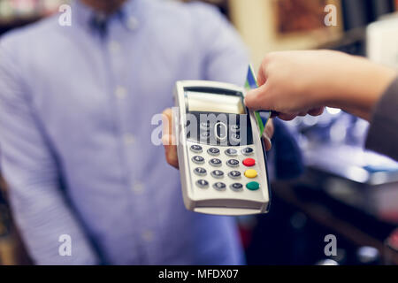 Bild des Verkäufers mit Stift in der Hand und Käufer mit der Kreditkarte. Stockfoto