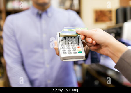 Foto der männlichen Verkäufer mit Stift in der Hand und die Käufer mit der Kreditkarte. Stockfoto