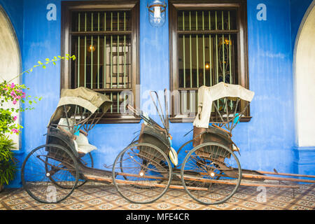 Alte Rikschas auf der blauen Wand, Cheong Fatt Tze Mansion, blaue Villa, Leith Street in Georgetown, Penang, Malaysia Stockfoto