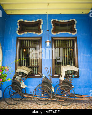 Alte Rikschas auf der blauen Wand, Cheong Fatt Tze Mansion, blaue Villa, Leith Street in Georgetown, Penang, Malaysia Stockfoto