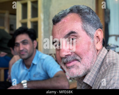 Kang, Iran - 30. Juli 2016: portrait eines iranischen Mann mit seiner Familie im Hintergrund Stockfoto