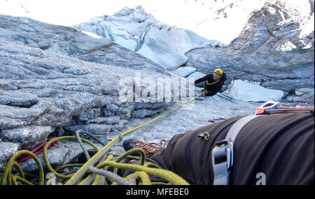 Bergführer auf einer harten Granit Aufstieg zu einer hochalpinen Gipfel in den Schweizer Alpen Stockfoto