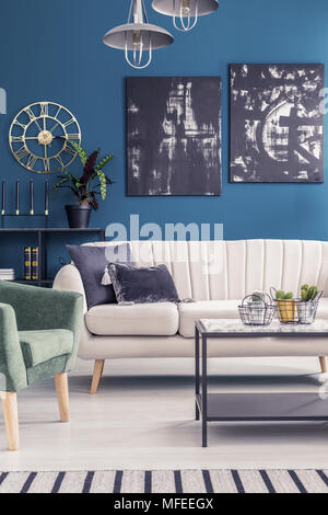 Gold und Schwarz Gemälde auf blauen Wand im Wohnzimmer Einrichtung mit Sofa unter Lampen Stockfoto