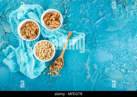 Einstellen der verschiedenen Arten von Nüssen - Erdnüsse in Schalen, Pinienkernen auf blauem Hintergrund Stockfoto