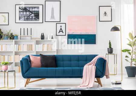 Marine Blau Sofa, Kissen, rosa Decke und Kunstsammlung im Wohnzimmer Innenraum Stockfoto