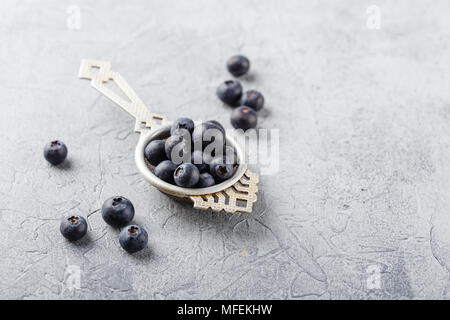 Blaubeeren oder Heidelbeeren in einem antiken Teesieb auf grauem Hintergrund. Gesundes Essen und Ernährung Konzept. Lecker saftig frische organische Beeren. Stockfoto