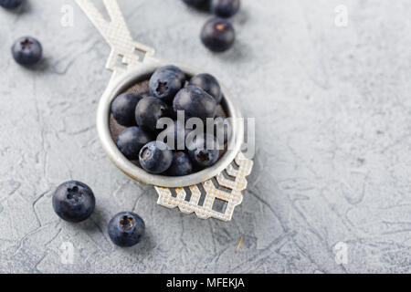 Blaubeeren oder Heidelbeeren in einem antiken Teesieb auf grauem Hintergrund. Lecker saftig frische organische Beeren. Gesundes Essen und Ernährung Konzept Stockfoto