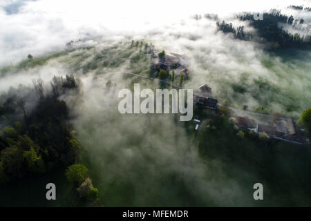 Luftaufnahme Nebel Wolken über eine Farm an einem Frühlingsmorgen in der Schweiz ziehen. Stockfoto