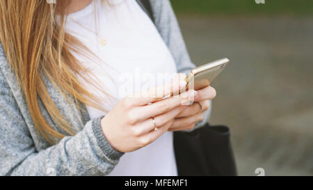 Nicht erkennbare junge Frau mit Smartphone oder Handy im Freien Stockfoto