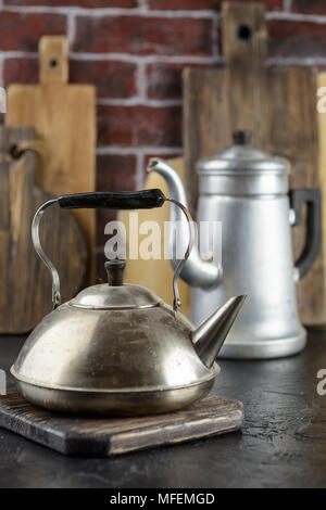 Alte Metall Wasserkocher und Kaffeemaschine auf einer Ziegelwand Hintergrund Stockfoto