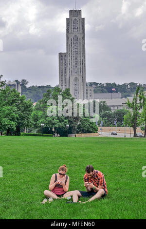 Paar Studenten auf dem Gras vor der Kathedrale von Lernen Universität von Pittsburgh, Pennsylvania, USA sitzen Stockfoto
