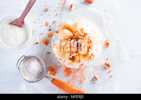 Knäckebrot mit karamellisierten Bananen, Frischkäse, griechischer Joghurt und Walnüsse. Gesundes Frühstück Konzept in einer High Key. Stockfoto