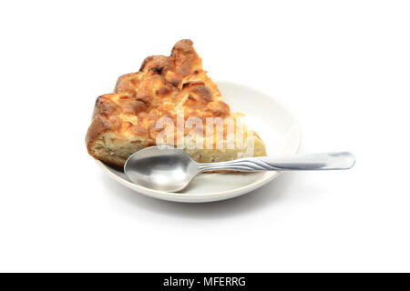 Stück Kuchen und Löffel liegen auf soucer auf weißem Hintergrund Stockfoto