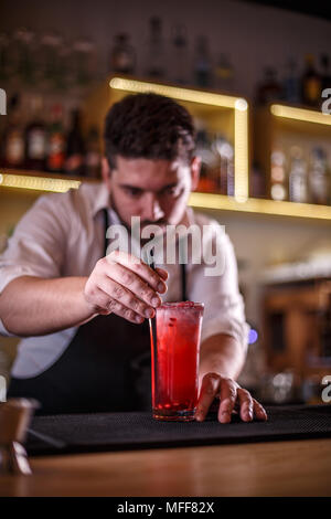 Barkeeper hinzufügen Kunststoff Stroh zu nicht-alkoholischen Granatapfel cocktail Stockfoto