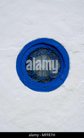 Runde Fenster mit einem blauen Rahmen mit einem gemusterten Grill auf eine weiße Wand in Tunesien Stockfoto