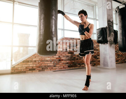 In voller Länge Porträt der passende Frau lernen Muay Thai Boxen und stehen auf Zehenspitzen an Gym. Meister der Boxing Sport Stockfoto