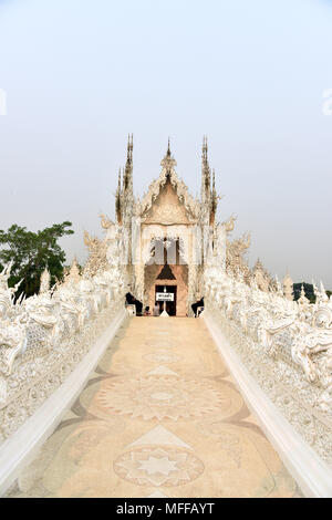 Die Brücke von der Zyklus der Wiedergeburt führt zu den wichtigsten Gebäude (Ubosot) von Wat Rong Khun oder der weiße Tempel in Chiang Rai, Nordthailand Stockfoto