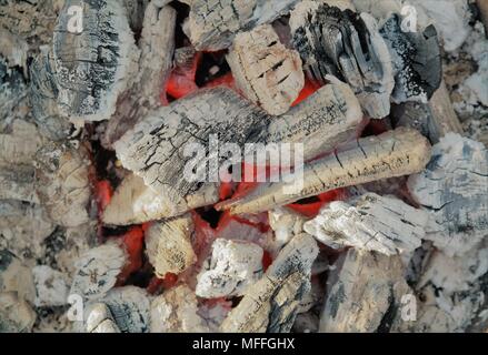 Ansicht von oben auf Holzkohle, weiß-graue Farbe. Die orangefarbene Farbe der brennenden Kohlen am Boden eines Grills. Stockfoto