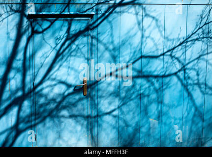 Schatten der Bäume und Äste auf der Seite des blauen Portable Kabinentür Stockfoto