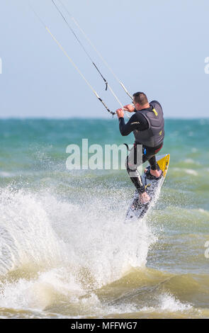 Man Kitesurfen am Meer und ein Spritzer Wasser in den Wasserbehälter. Kitesurfer bei einer Bremsung. Porträt Stockfoto