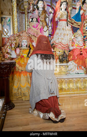 Eine Anbeterin niederknien und beten zu dem Gott Shiva in der Shri Lakshmi Narayan Mandir Tempel in Richmond Hill, Queens, New York. Stockfoto