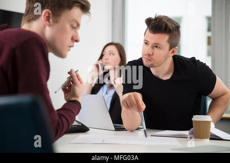 Professionelle Planung, während Kollege mittels Smart Phone In Offi Stockfoto