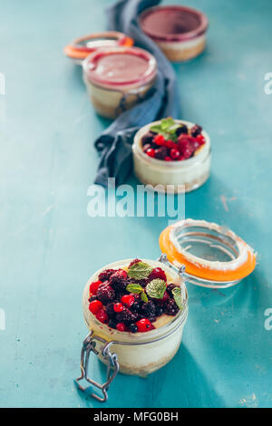 Käsekuchen mit Beeren gefüllt auf ein .jar über einen aqua Rusty Hintergrund, Tageslicht nur. Stockfoto