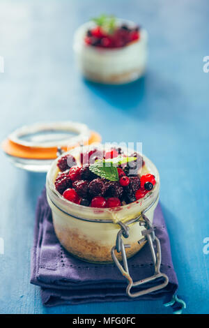 Käsekuchen mit Beeren gefüllt auf ein .jar über einen aqua Rusty Hintergrund, Tageslicht nur. Stockfoto