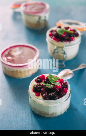 Käsekuchen mit Beeren gefüllt auf ein .jar über einen aqua Rusty Hintergrund, Tageslicht nur. Stockfoto